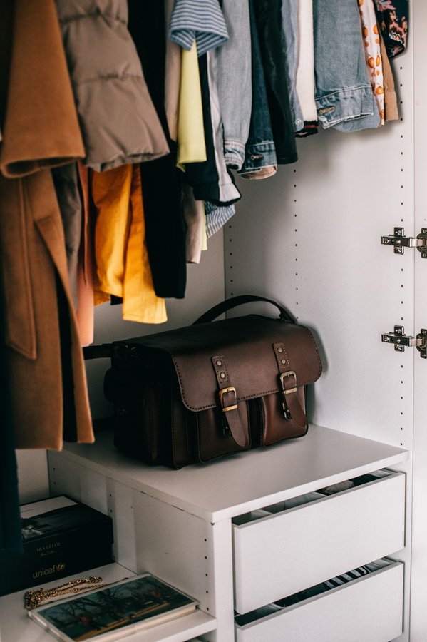 Closet before seasonal rotation showing mixed-season clothing and storage chaos